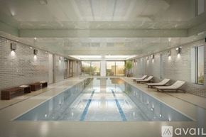 Queens apartment for rent - A large indoor swimming pool with lounge chairs on the side.