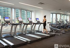 Manhattan apartment for rent - A woman is running on a treadmill in a gym with other treadmills and exercise equipment.