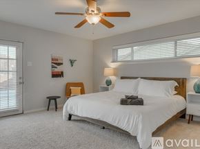 Garland house for rent - A bedroom with a large bed, a ceiling fan, and a nightstand with a lamp.
