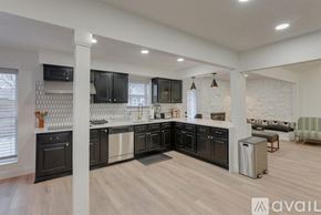 North Richland Hills house for rent - A modern kitchen with black cabinets and a wooden floor.