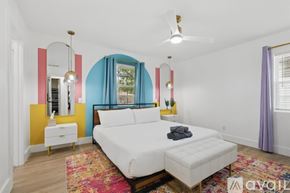 Dallas house for rent - A bedroom with a white bed and a colorful accent wall.