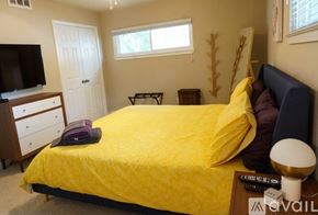 Irving house for rent - A bedroom with a bed covered in yellow bedding and a white lamp on the nightstand.