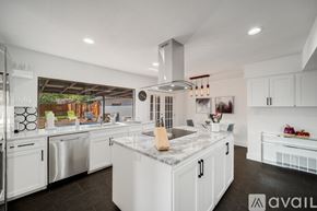 Grand Prairie house for rent - A modern kitchen with white cabinets and a marble island.