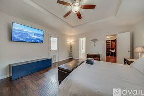 Plano house for rent - A bedroom with a large bed and a flat screen TV mounted on the wall.