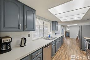 Carrollton house for rent - A kitchen with dark cabinets and a white countertop.