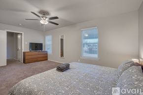 Dallas house for rent - A bedroom with a large bed and a ceiling fan.