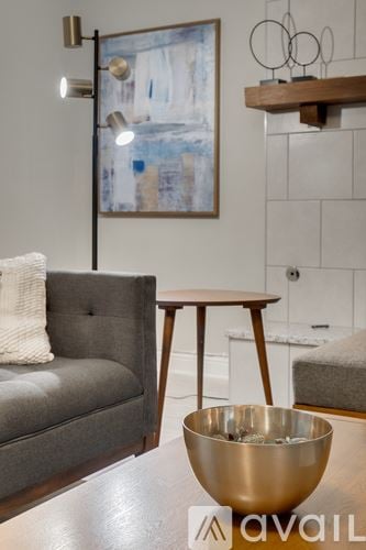 Dallas house for rent - A grey couch with a white pillow sits in a living room with a wooden table and a bowl on it.