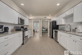 Dallas house for rent - A kitchen with white cabinets and a wooden floor.