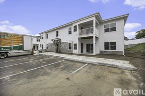 Grand Rapids apartment for rent - A white two-story building with a balcony on the second floor and a parking lot in front.