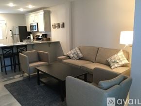 Ruston apartment for rent - A modern living room with a grey couch and a kitchen area in the background.