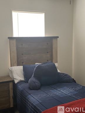 Ruston house for rent - A bed with a wooden headboard and blue bedding with a window above it.