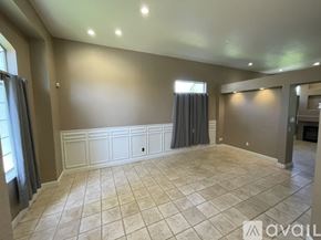 Sacramento house for rent - A spacious room with tiled flooring and a window with curtains.