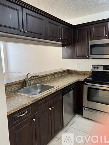West Palm Beach condo for rent - A kitchen with dark brown cabinets and stainless steel appliances.