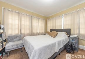 Cleveland Heights house for rent - A bedroom with a bed, chair, and window with curtains.