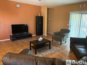 Phoenix apartment for rent - A living room with a brown leather couch, a black coffee table, a black television, and a black bookshelf.