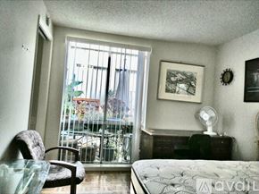 Laguna Woods condo for rent - A bedroom with a bed, chair, and window.