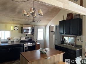 Bitely house for rent - A kitchen with a wooden table and black cabinets.