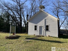 Bitely house for rent - A small white church with a bell tower stands alone in a grassy field.