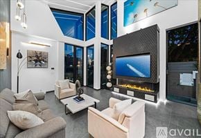 Los Angeles house for rent - A modern living room with a large flat screen TV and a fireplace.