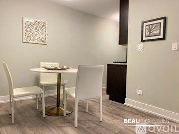 Chicago apartment for rent - A living room with a white couch, a coffee table with a plant and books on it, and a painting on the wall.