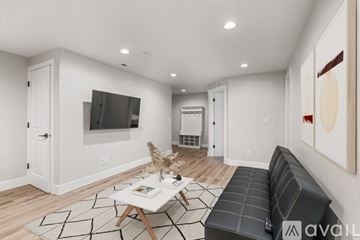 Lehi apartment for rent - A living room with a black couch, a coffee table, and a television on the wall.
