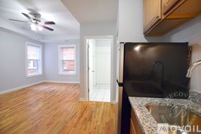 Chicago apartment for rent - A kitchen with a black fridge and wooden floors.