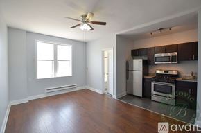 Chicago apartment for rent - A living room with a wood floor and a kitchen area in the background.