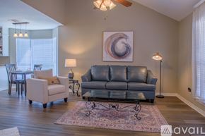 Shreveport townhouse for rent - A living room with a grey couch, a white chair, and a rug.