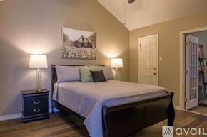Shreveport townhouse for rent - A bedroom with a bed, nightstand, and a painting on the wall.