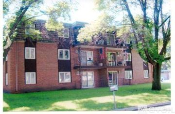 Willmar apartment for rent - A red brick building with a balcony and a tree in front.