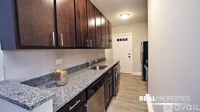 Chicago apartment for rent - A kitchen with granite countertops and wooden cabinets is available for rent.