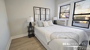 Chicago apartment for rent - A bedroom with a large bed and a window overlooking a city street.