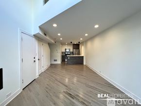 Chicago apartment for rent - A spacious room with wooden flooring and a white door.