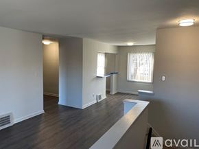 Detroit apartment for rent - A spacious room with wood flooring and white walls.