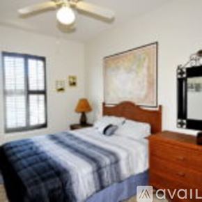 Corpus Christi condo for rent - A bedroom with a bed, a ceiling fan, a nightstand with a lamp, and a painting on the wall.