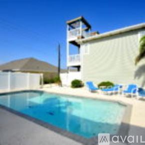 Corpus Christi condo for rent - A swimming pool in front of a house with a deck and chairs.