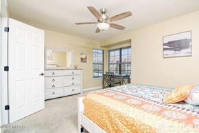 Tucson condo for rent - A bedroom with a bed, dresser, and ceiling fan.