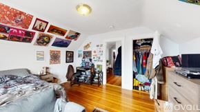 Somerville apartment for rent - A bedroom with a bed, a chair, and a wall covered in pictures.