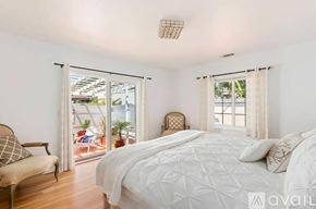 Santa Barbara house for rent - A bedroom with a large bed and a chair by the window.