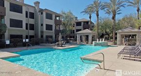 Phoenix apartment for rent - A large swimming pool surrounded by palm trees and lounge chairs.