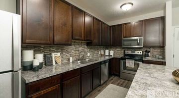 Sunbury apartment for rent - A kitchen with dark wood cabinets and a granite countertop.