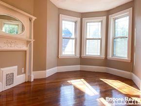 Boston apartment for rent - A sunlit room with a fireplace and three windows.