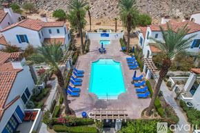 La Quinta townhouse for rent - A pool surrounded by palm trees and lounge chairs.