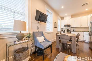 Boston apartment for rent - A living room with a grey chair and a glass table with a lamp and a plant on it.