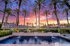 La Quinta house for rent - A pool surrounded by palm trees at sunset.