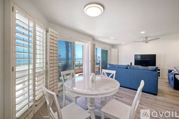 Oceanside apartment for rent - A modern living room with a white dining table and chairs, a blue sofa, and a television.