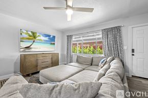 Fort Lauderdale apartment for rent - A living room with a large couch, a dining table with chairs, and a painting of a beach scene on the wall.