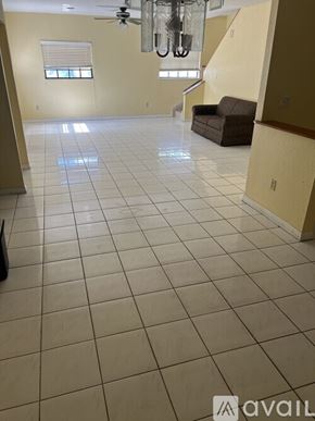 Miami Gardens house for rent - A spacious room with a fan and a brown couch.