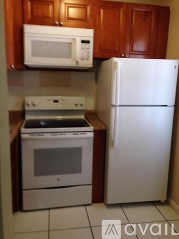 Lauderhill apartment for rent - A white refrigerator stands next to a white microwave and an oven in a kitchen.