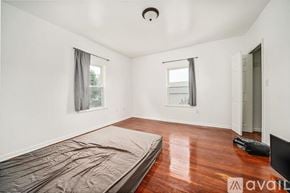 Quincy apartment for rent - A bedroom with a bed covered in a grey blanket and a television on the right side.